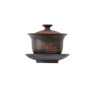 Handcrafted Jianshui zitao lotus-patterned black Gaiwan tea bowl with intricate line-carved floral design and matching saucer