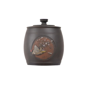 Unglazed, hand-polished pottery tea canister featuring an incised-and-filled landscape scene, with a matte dark clay body and detailed scenic artwork on the front.