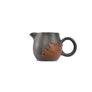 Side view of a Jianshui zitao fairness pitcher featuring hand-applied lotus leaf relief carving on the pottery body