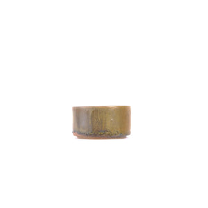 Side view of a wood-fired Jianshui zitao tea cup showing natural ash deposits and kiln-fired surface variation