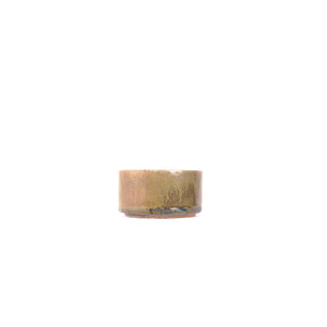 Side view of a wood-fired Jianshui zitao tea cup highlighting layered kiln marks and earthy surface tones