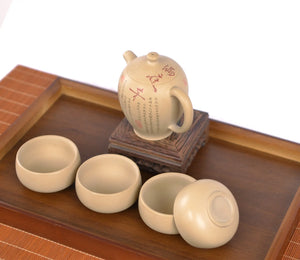 Angled view of a handcrafted white clay peony teapot set with four matching cups, featuring hand-carved floral and calligraphy details.