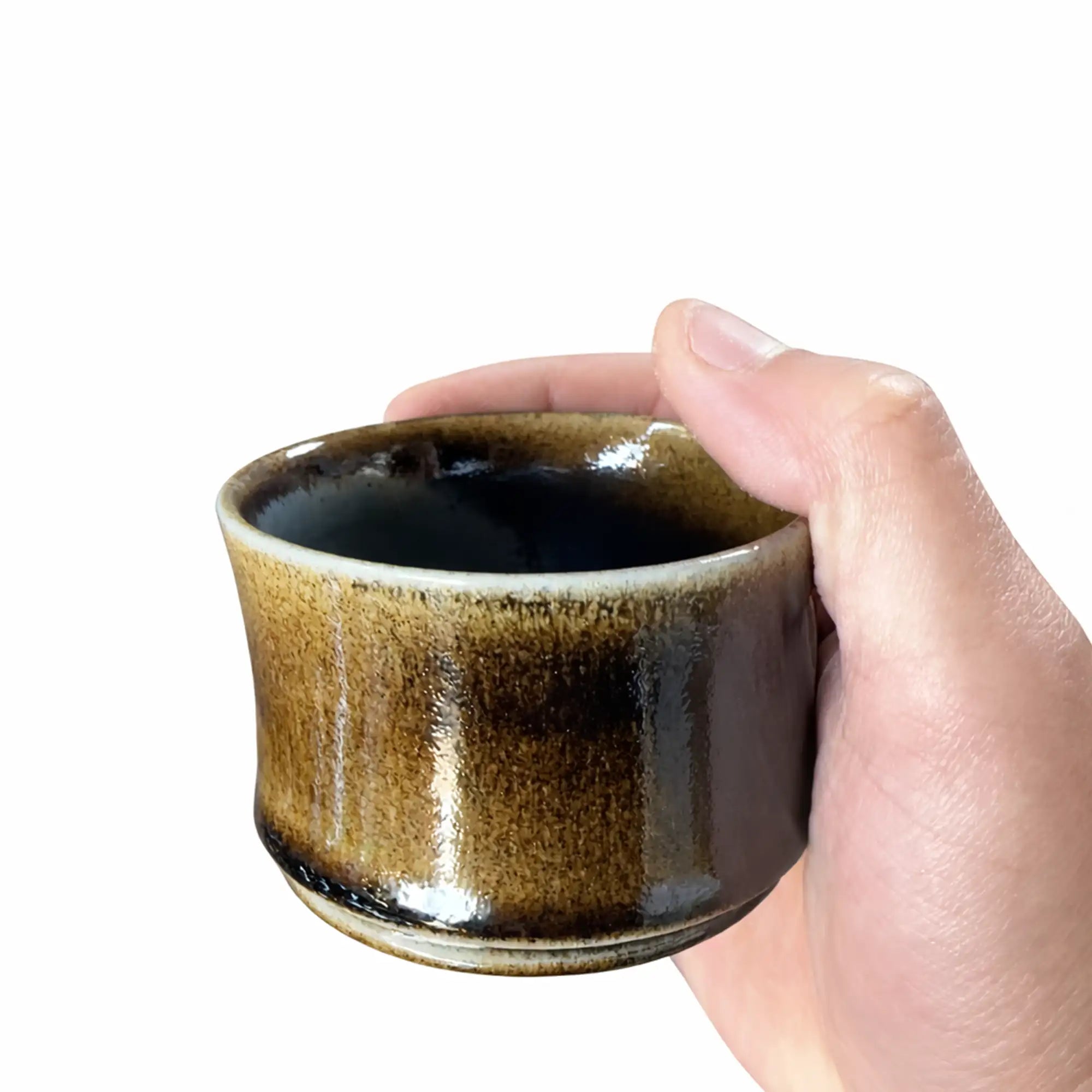 Handheld wood-fired Jianshui zitao tea cup showing natural kiln-fired glaze textures