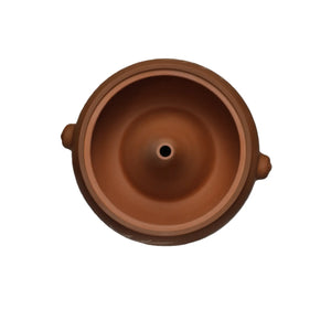 Top-down interior view of a handmade purple pottery steam pot (red clay), showing the central steam vent.