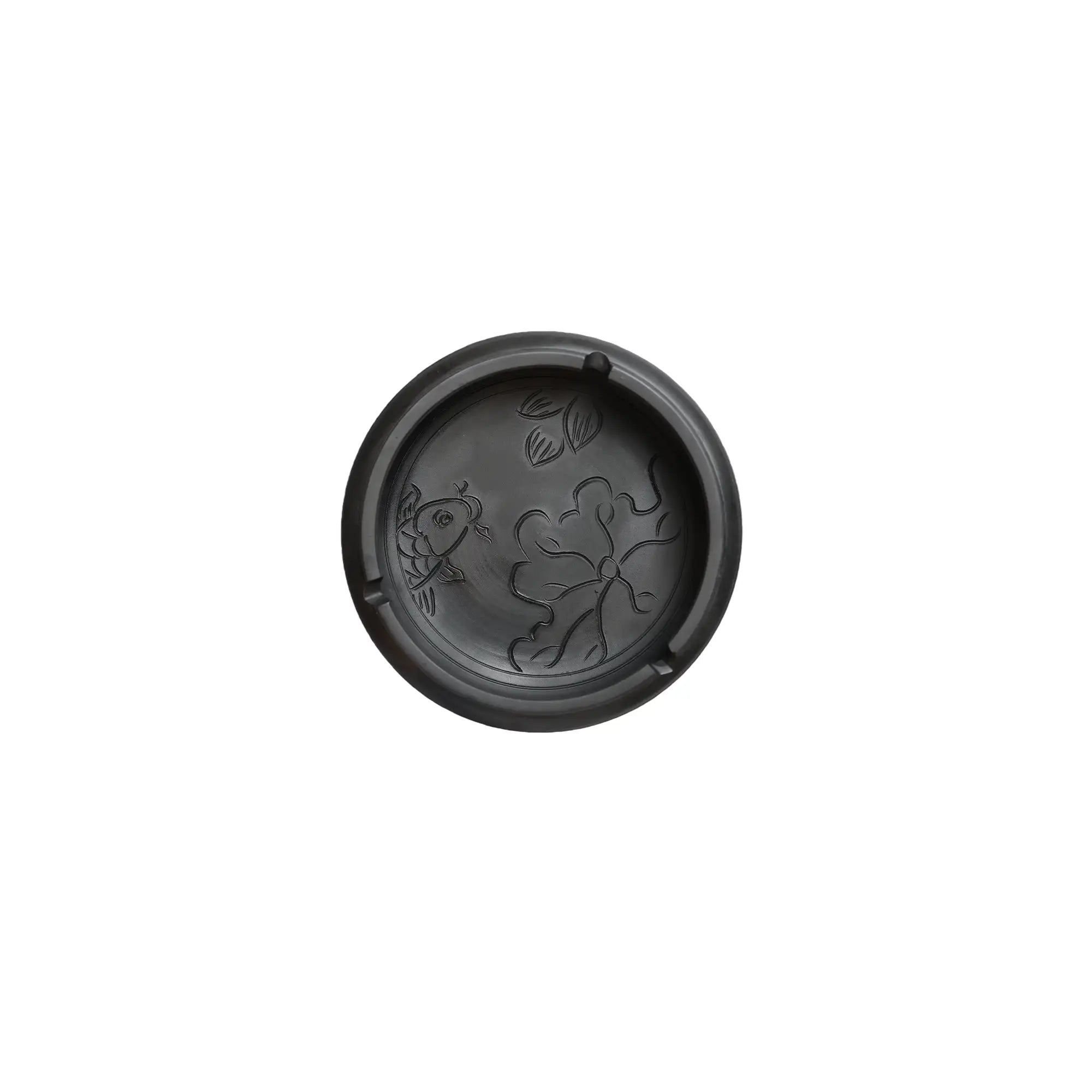 Top view of a handmade pottery ashtray with carved fish and lotus leaf design