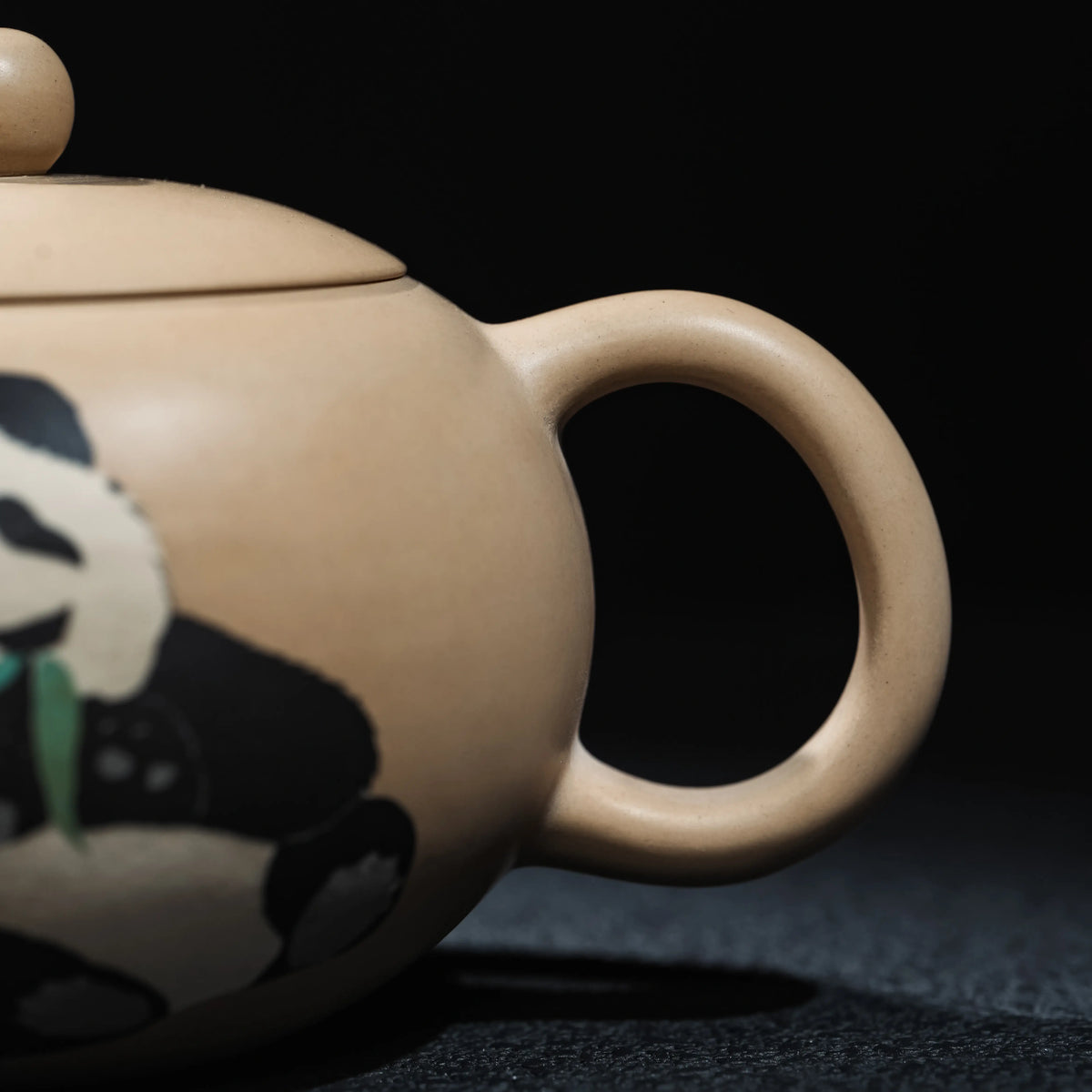 Side view showing the handle and panda motif of Jianshui teapot