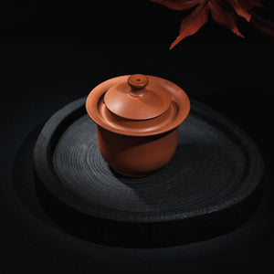 Angled view of handmade Jianshui plain red clay handleless teapot