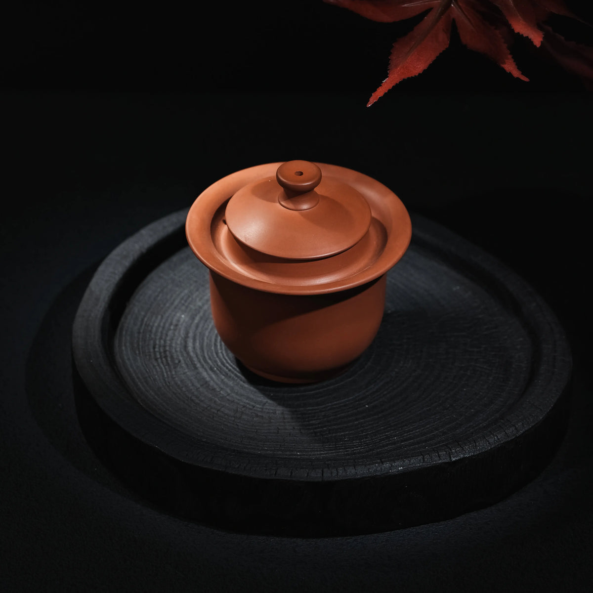 Angled view of handmade Jianshui plain red clay handleless teapot