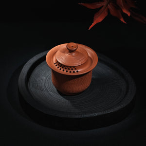 Angled view of Jianshui red clay handleless teapot with chattering texture