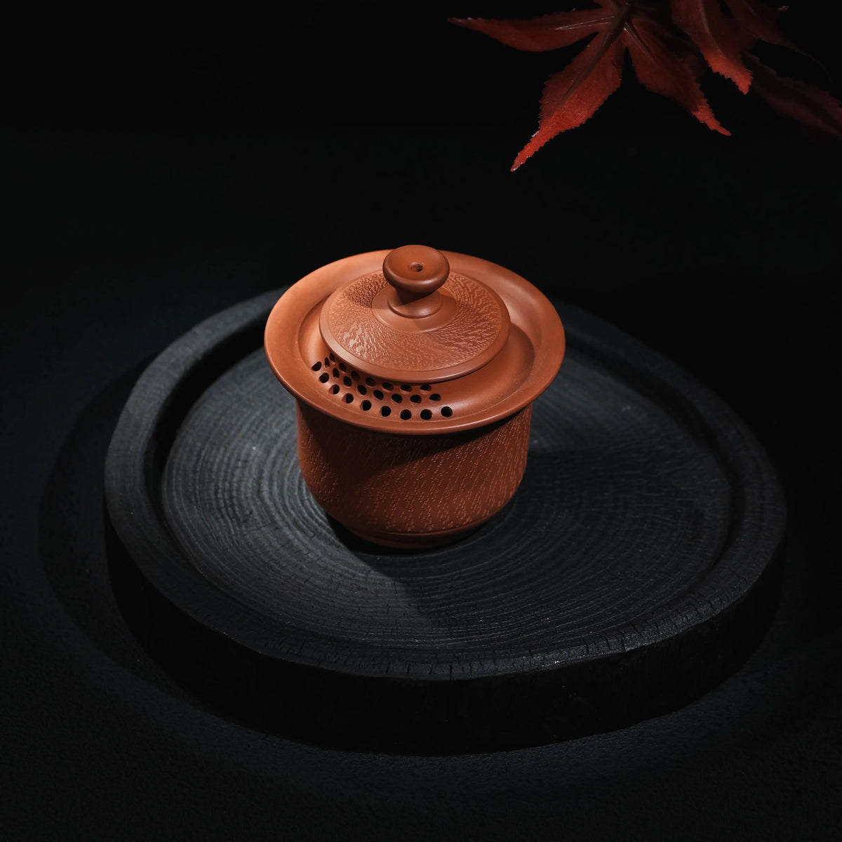 Angled view of Jianshui red clay handleless teapot with chattering texture