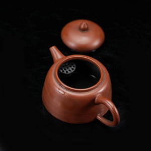 Open Jianshui red clay teapot showing the interior and filter