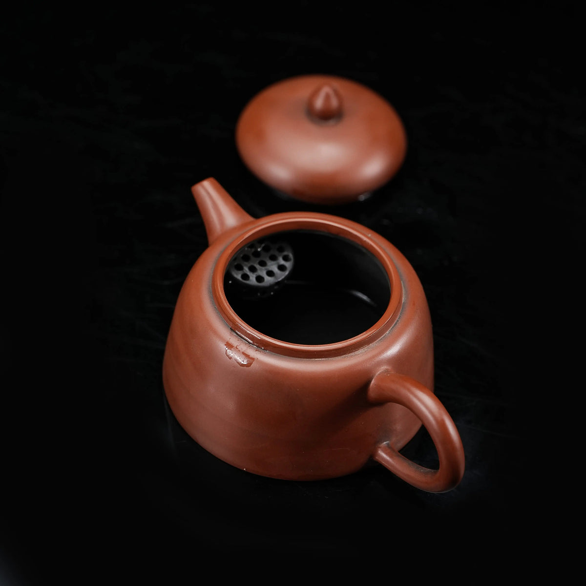 Open Jianshui red clay teapot showing the interior and filter