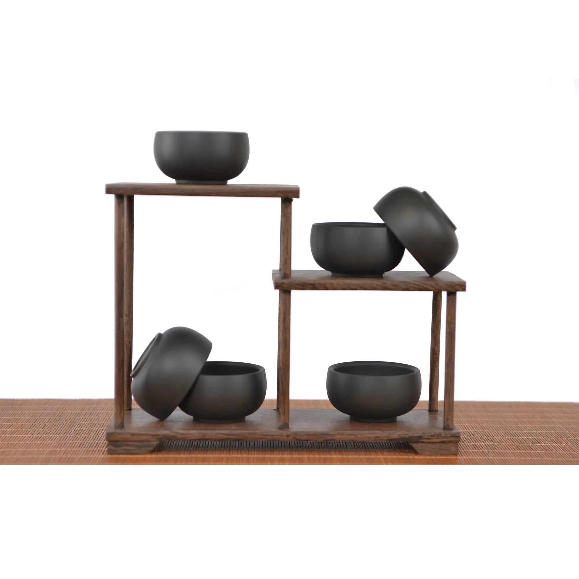 Six Jianshui zitao tea cups with a matte black finish on a tiered wooden stand