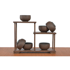 Jianshui zitao tea cups warm brown tone with a bodhi-leaf–inspired texture, arranged on a wooden display stand