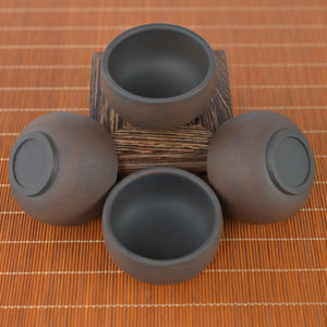 Top view of four Jianshui zitao tea cups warm brown tone with a bodhi-leaf–inspired texture, arranged around a wooden stand