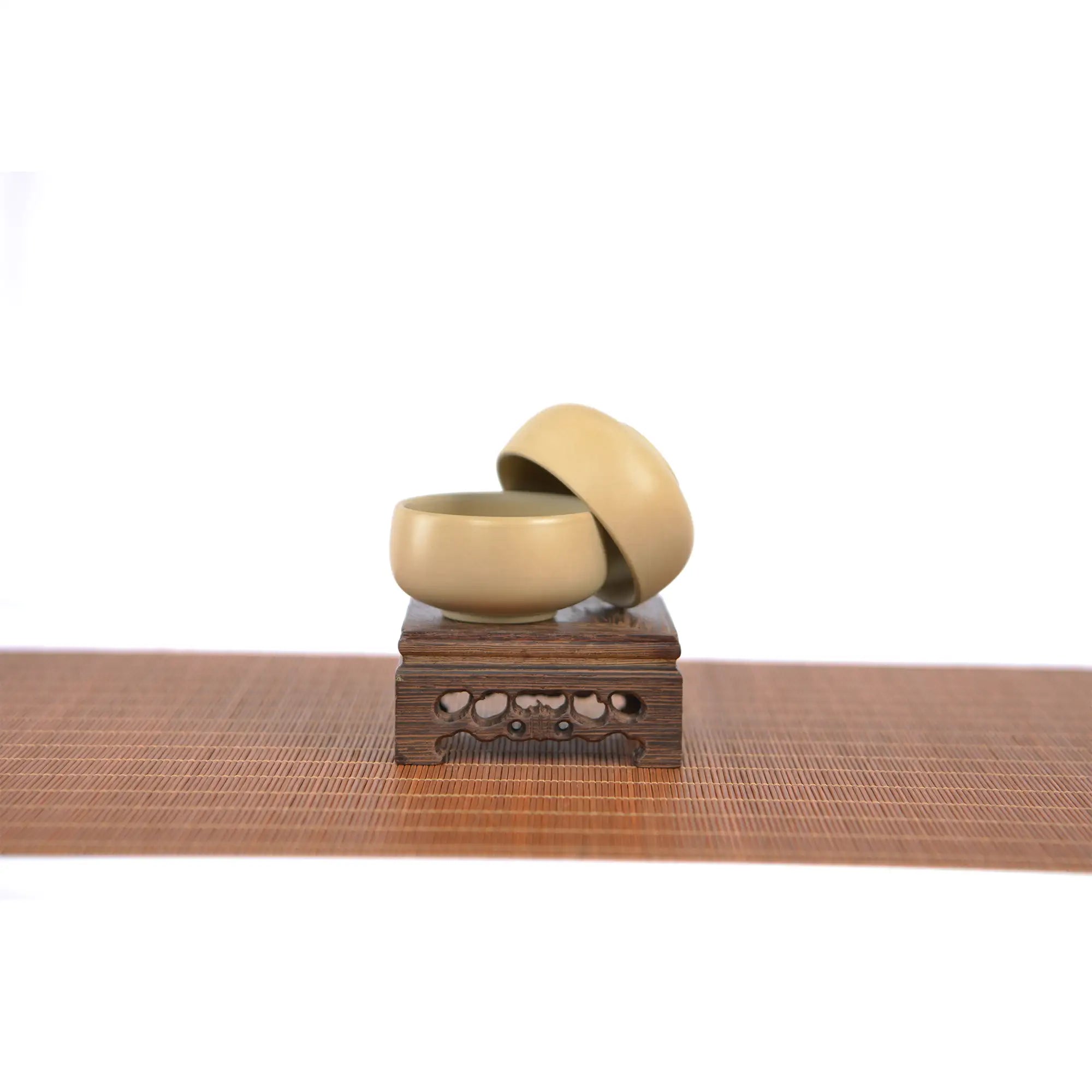 Two small light-toned Jianshui zitao teacups stacked on a carved wooden stand, featuring a smooth unglazed matte finish and minimalist design