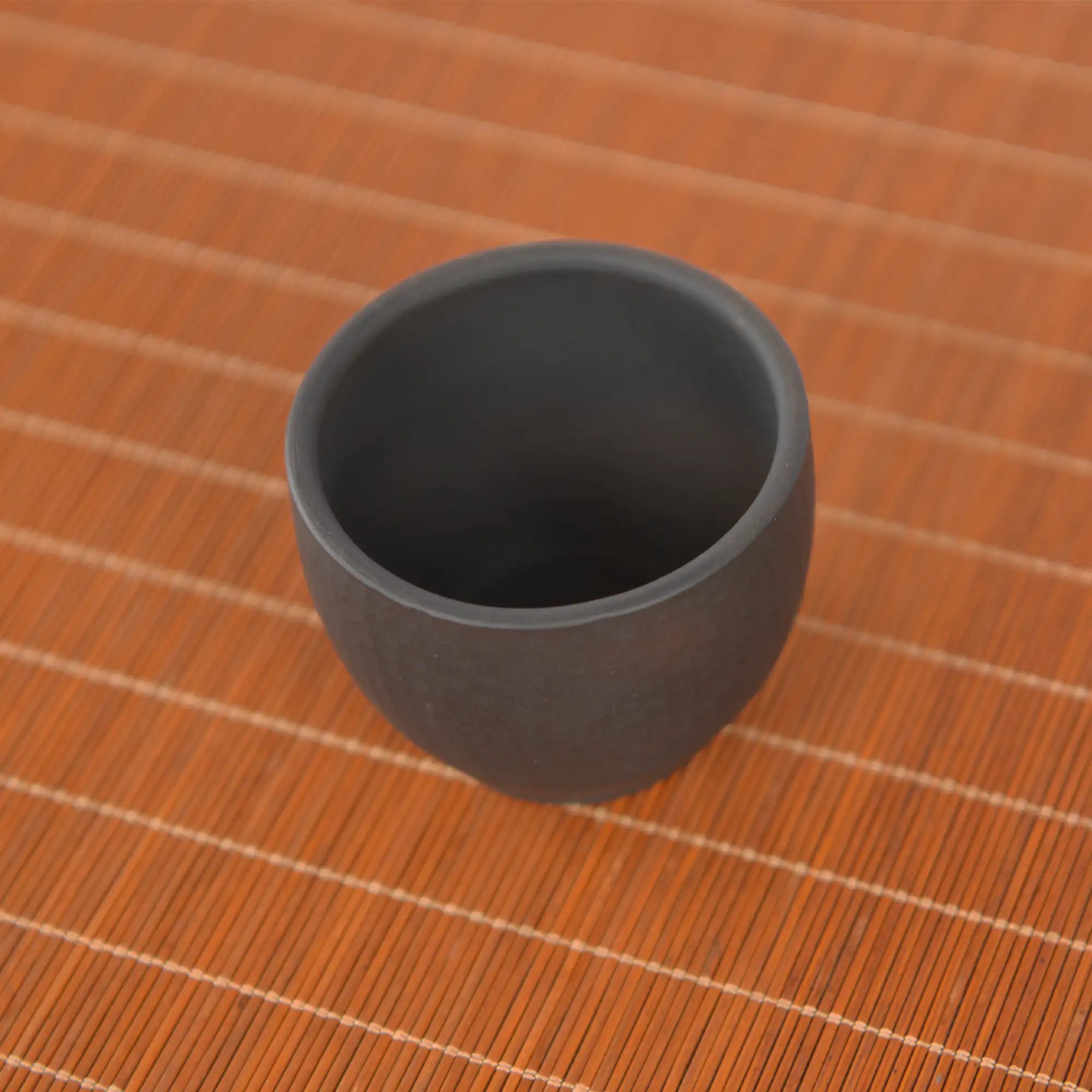 Top-down view of a Jianshui zitao dark clay master tea cup showing a smooth unglazed interior and thick rounded rim