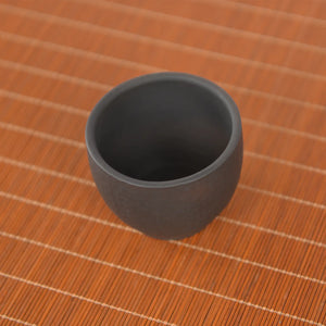 Top-down view of a Jianshui zitao dark clay master tea cup showing a smooth unglazed interior and thick rounded rim