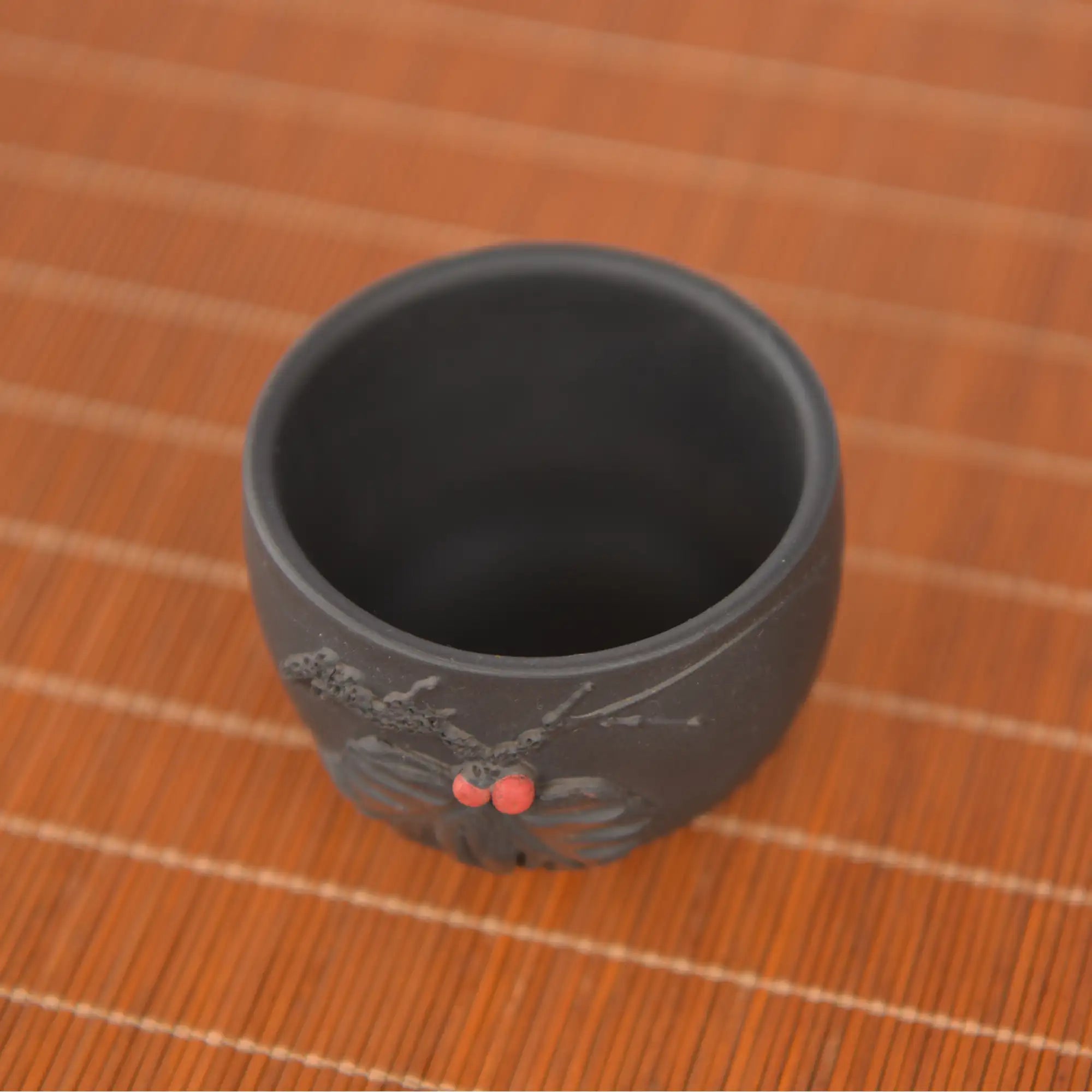 Jianshui zitao master tea cup with applied leaf relief carving, displayed on a carved wooden stand