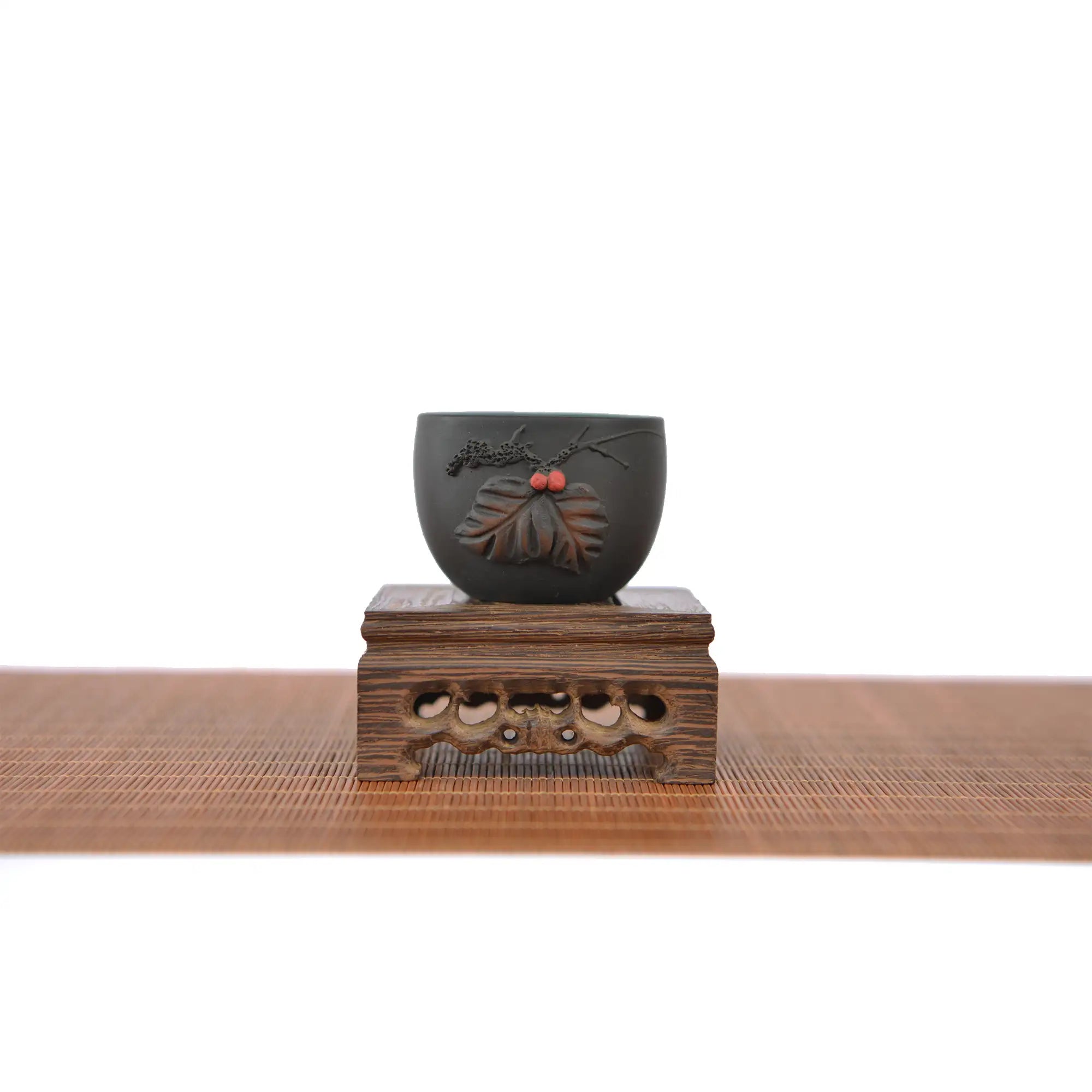 Jianshui zitao master tea cup with applied leaf relief carving, displayed on a carved wooden stand