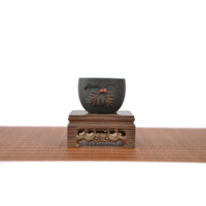 Jianshui zitao master tea cup with applied leaf relief carving, displayed on a carved wooden stand