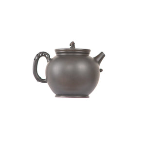 Jianshui zitao black clay teapot featuring a perforated handle design, side view.