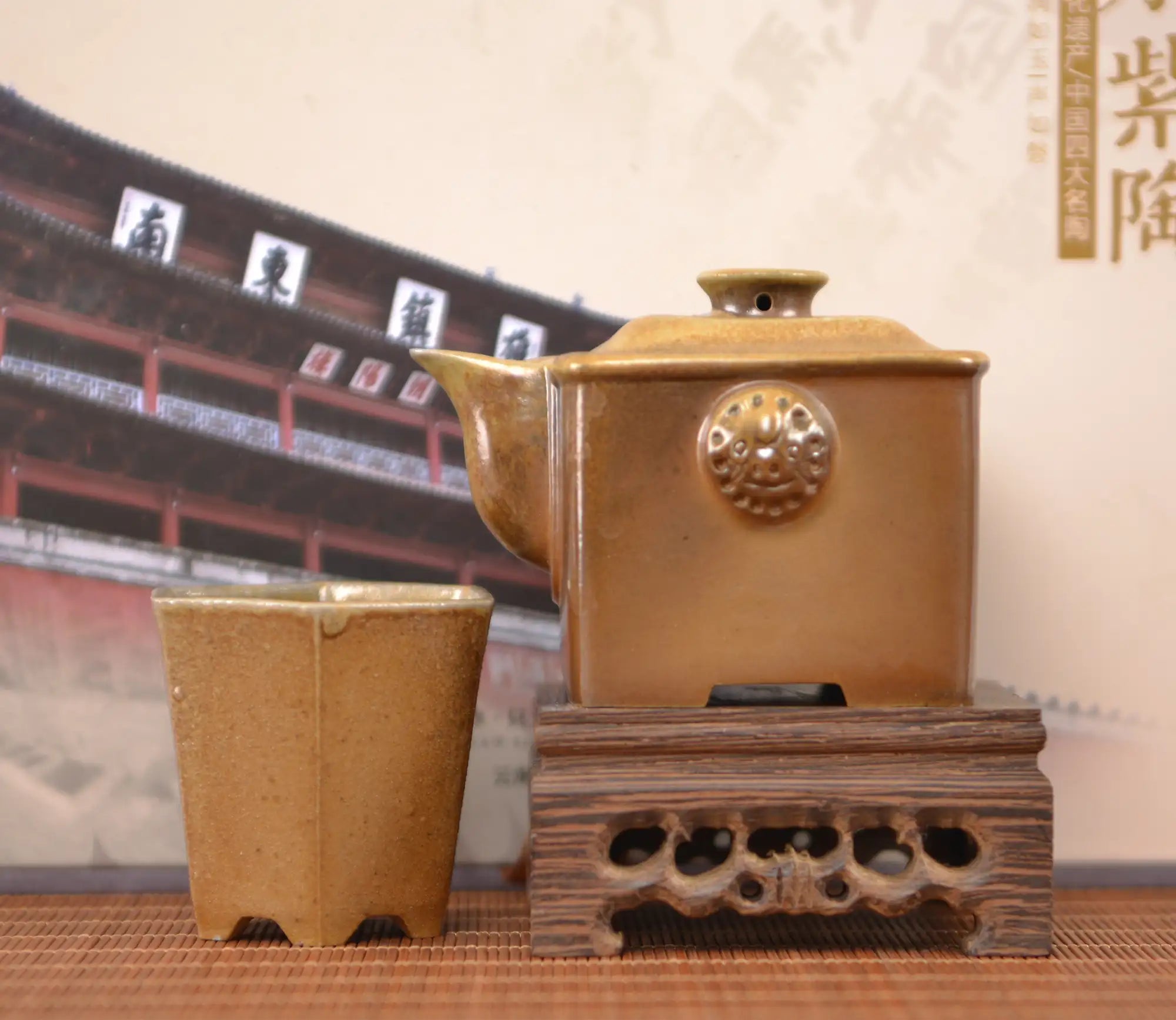 Wood-fired clay square teapot and matching cup set, displayed on a carved wooden stand