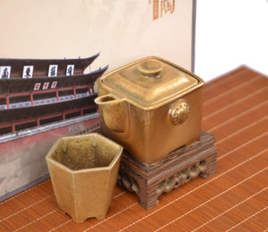 Wood-fired clay square teapot and cup set with natural ash glaze, displayed in a traditional setting