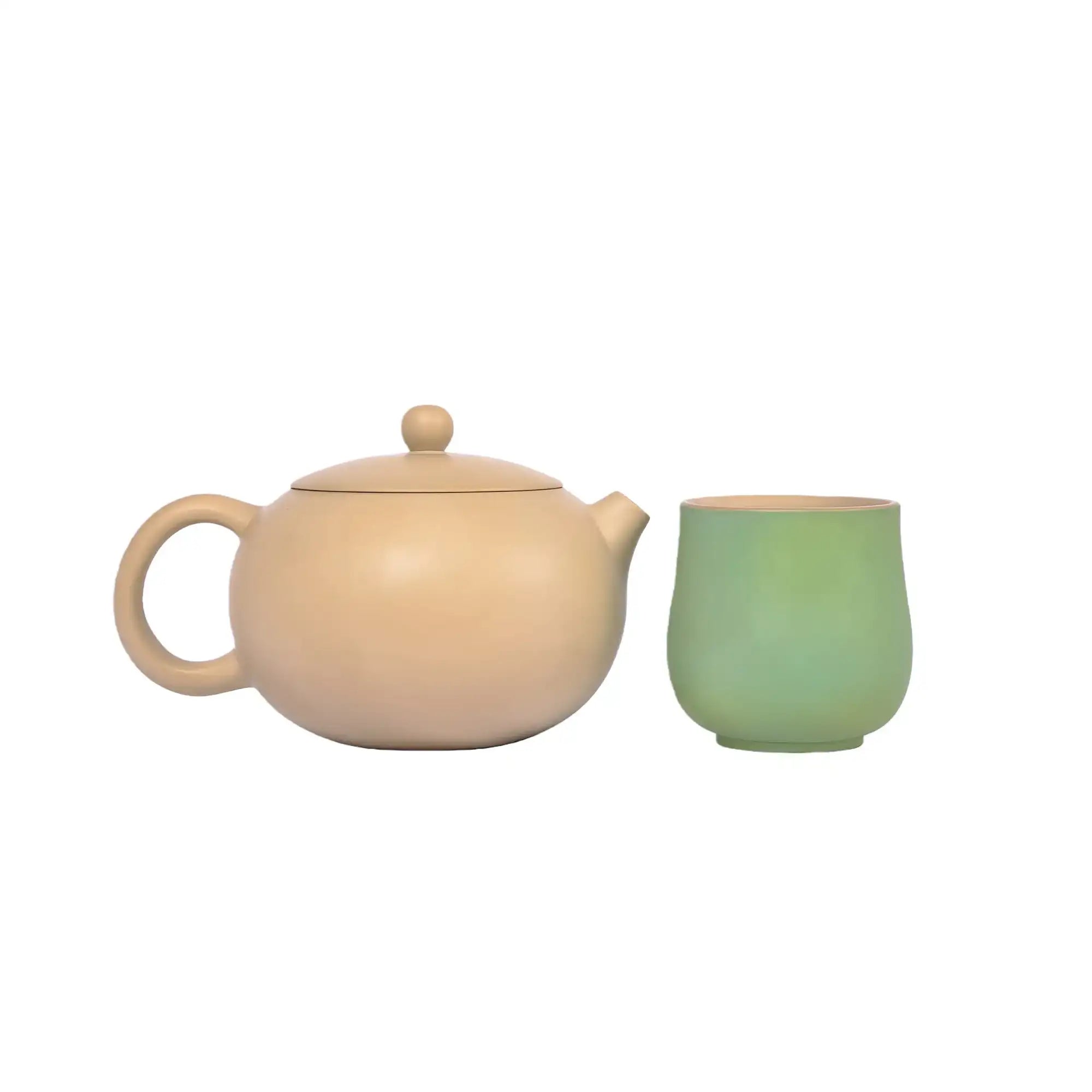 A beige, unglazed handcrafted Jianshui zitao teapot, paired with matching green teacups