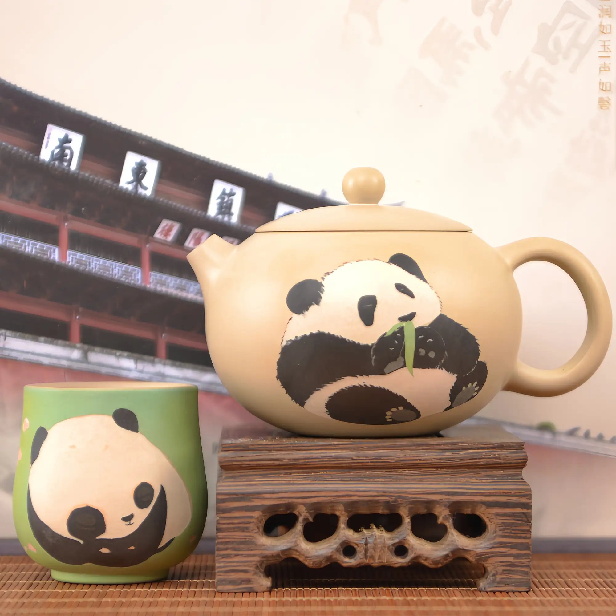Hand-engraved panda Jianshui zitao teapot and matching cup displayed on a wooden stand in a traditional setting