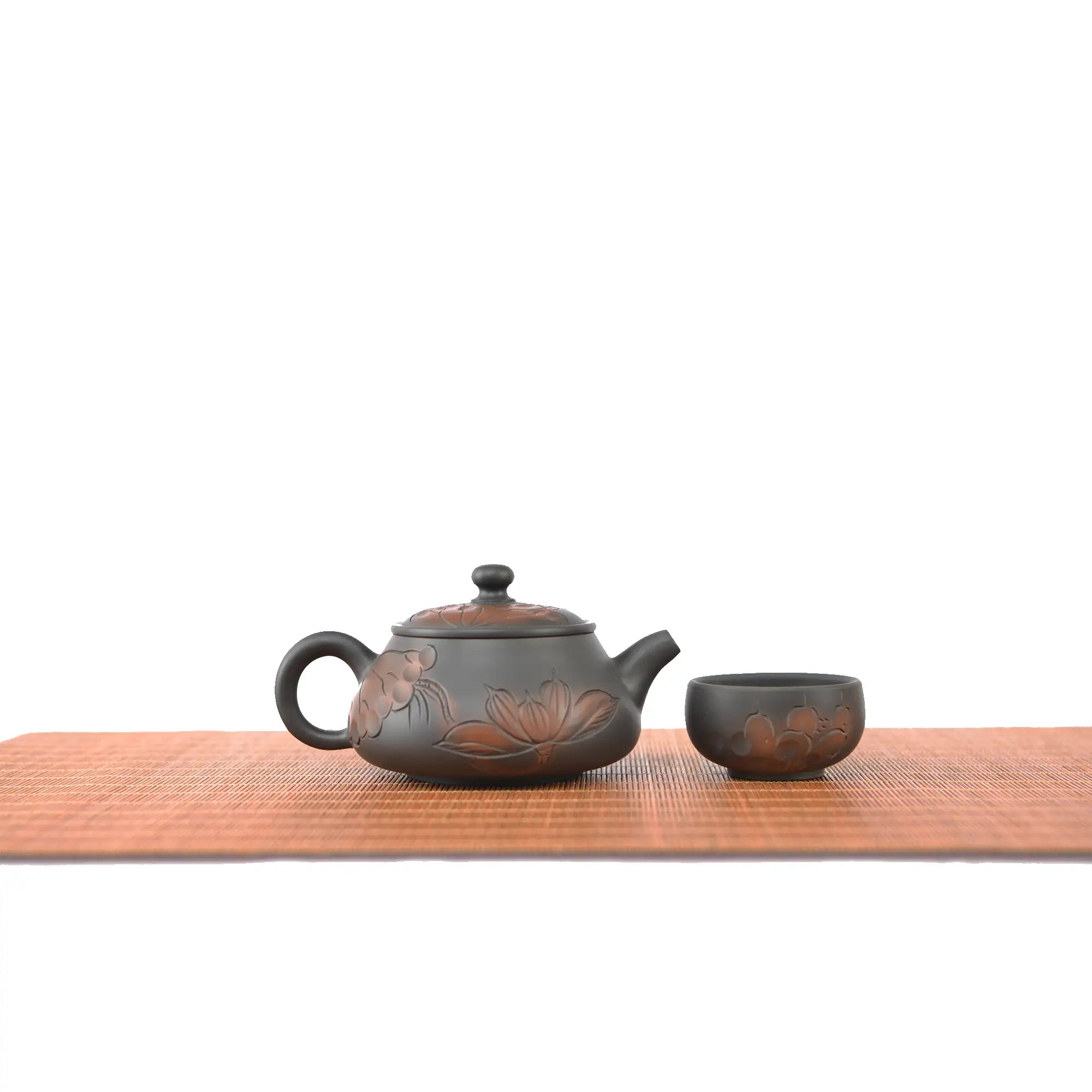 Handmade pottery Shi Piao teapot with a line-carved lotus design, displayed with one matching tea cup.
