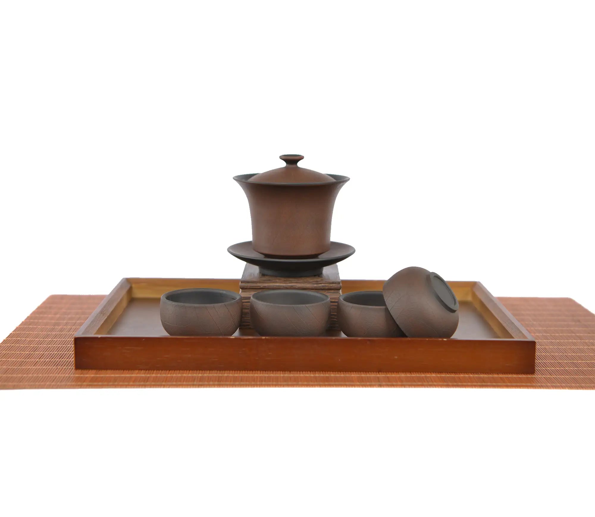 Warm brown Bodhi-pattern pottery gaiwan with saucer displayed on a carved wooden stand, paired with four matching teacups arranged on a rectangular tea tray, with one cup turned on its side