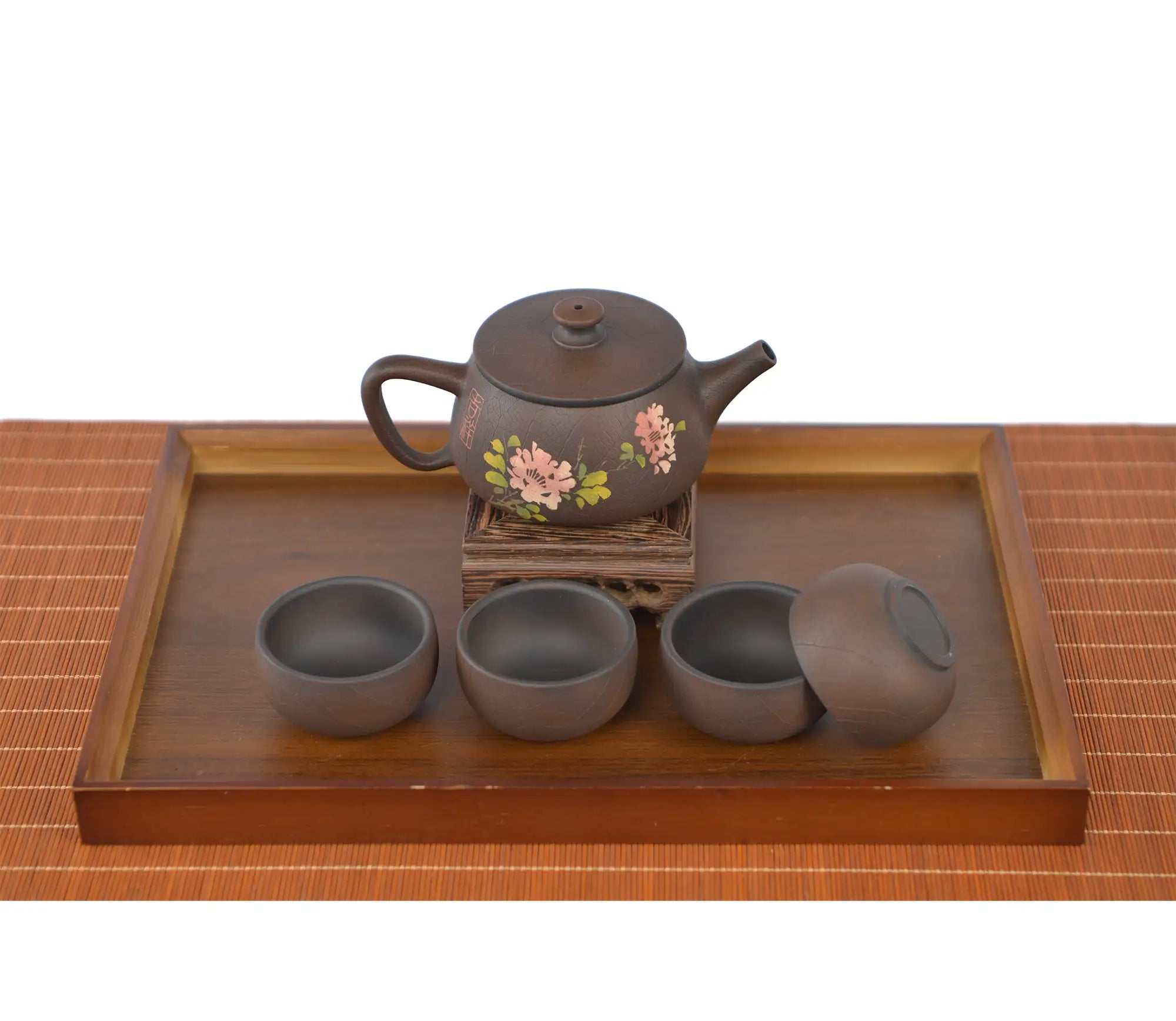 Handcrafted unglazed pottery teapot with a Bodhi-style crackle texture and engraved peony design, displayed with four matching teacups on a wooden tray.