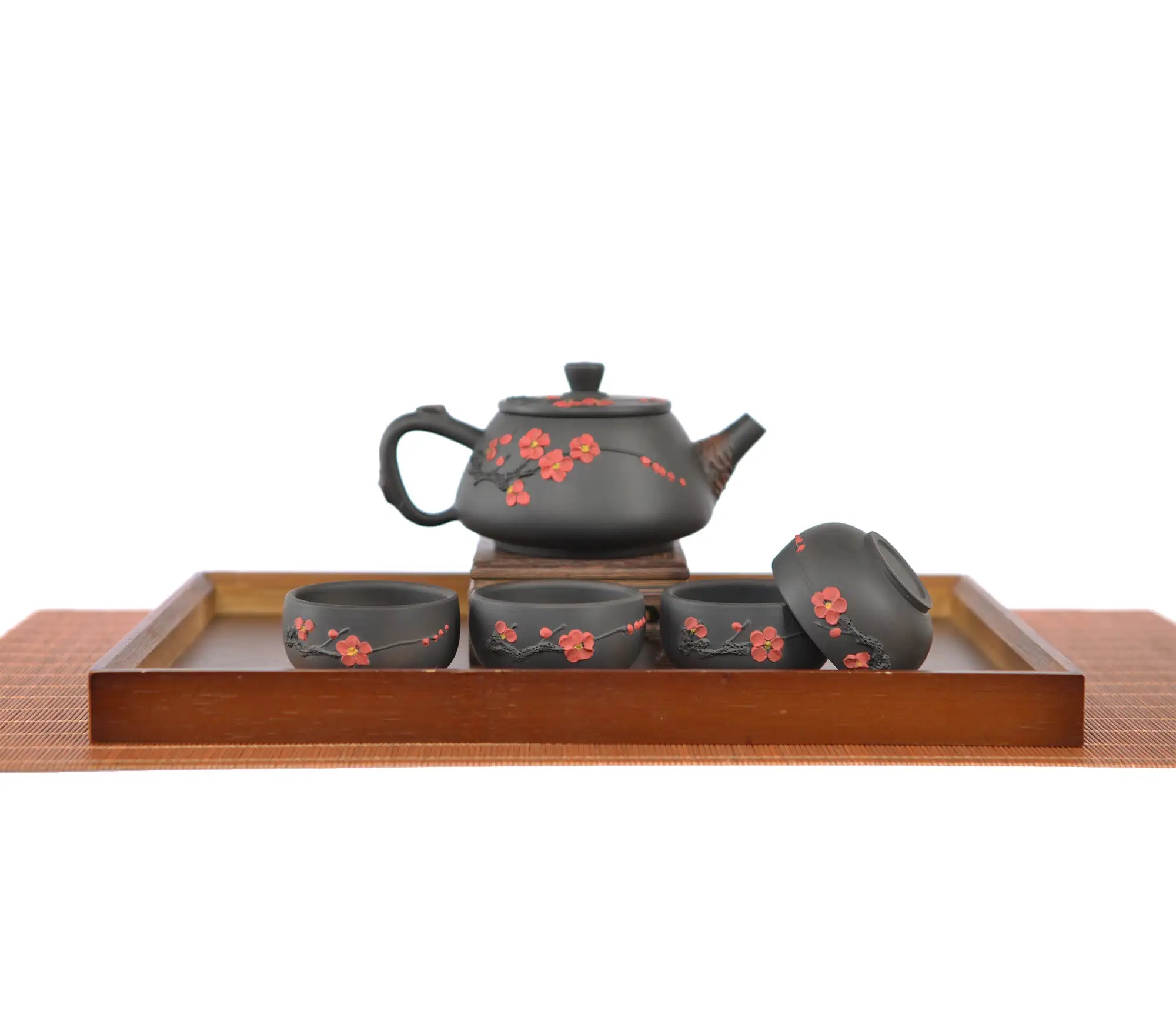 Jianshui zitao root-carved teapot with plum blossom detailing, displayed with four matching teacups on a wooden tea tray