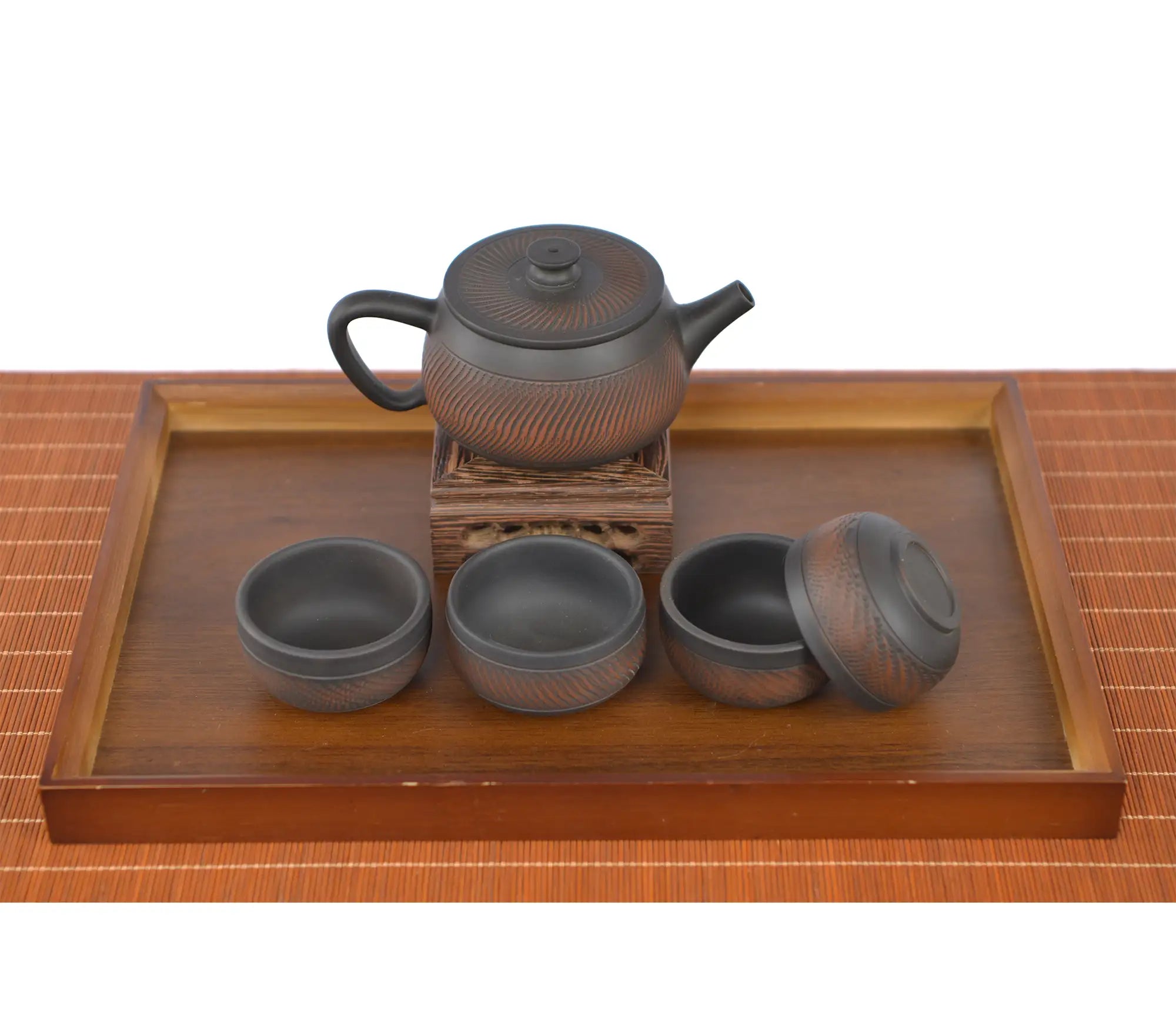 Traditional handcrafted pottery teapot featuring a chattered knife texture and natural unglazed finish, presented with matching teacups neatly arranged on a wooden serving tray.