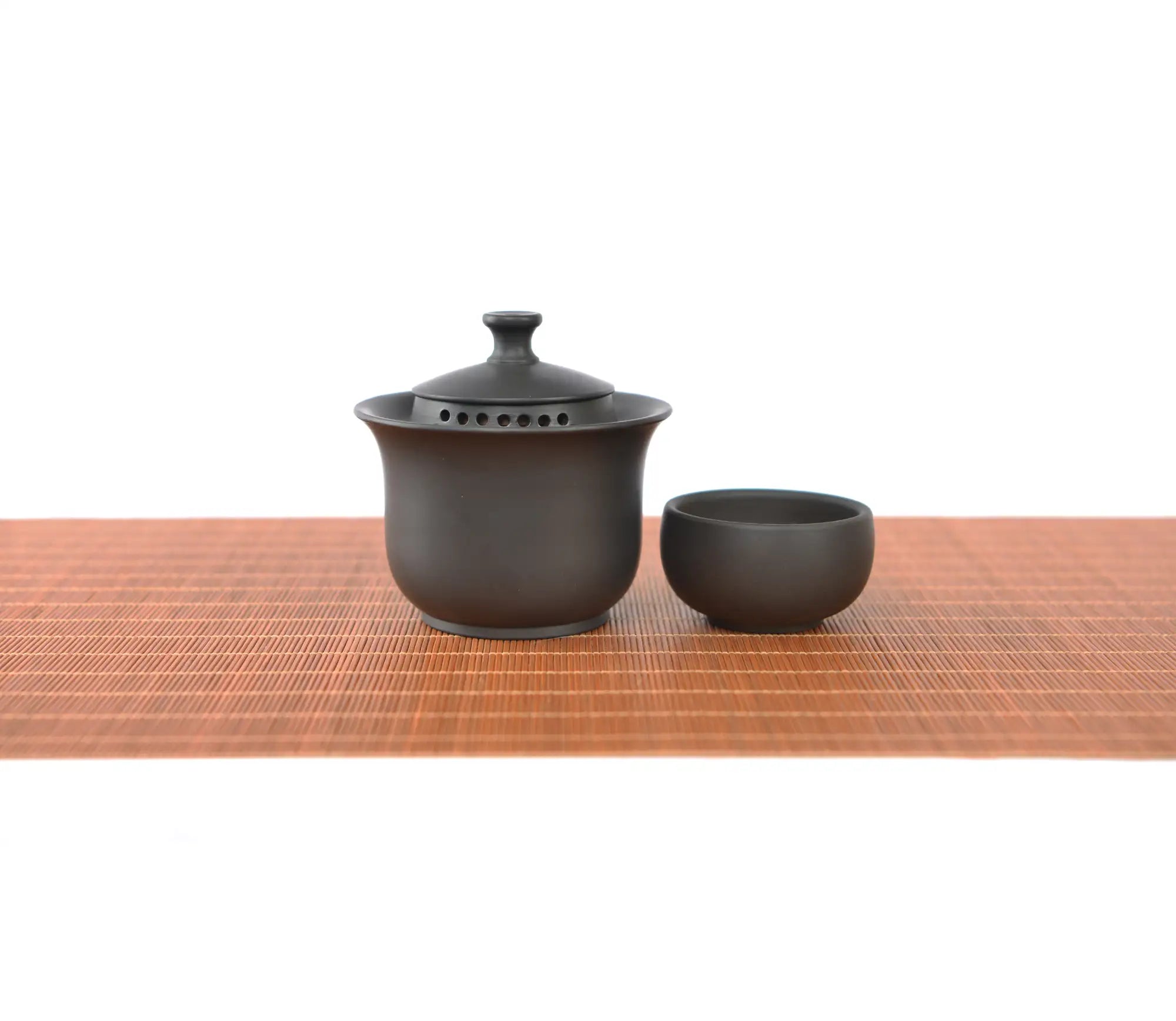 Handcrafted black pottery gaiwan set with finger-grip lid and built-in filter holes, featuring a minimalist tea bowl and matching cup.